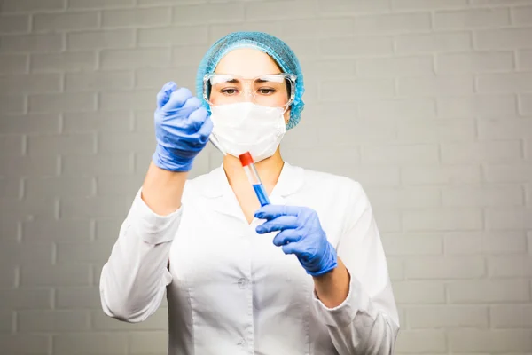 Science, chemistry, biology, medicine, people concept - young female scientist holding tube with sample making and test or research in clinical laboratory