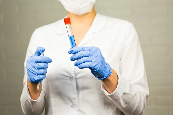 Science, chemistry, biology, medicine, people concept - young female scientist holding tube with sample making and test or research in clinical laboratory
