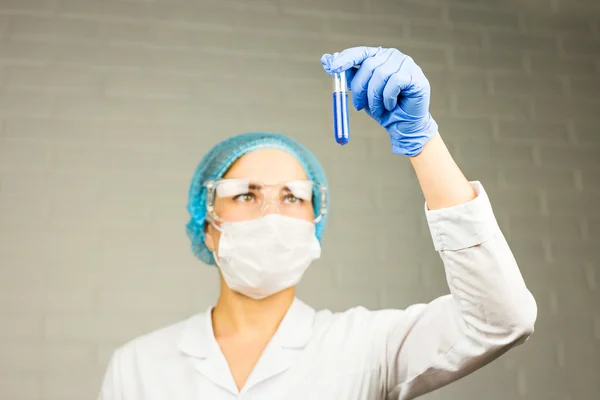 Science, chemistry, biology, medicine, people concept - young female scientist holding tube with sample making and test or research in clinical laboratory