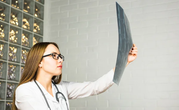 Closeup portrait of intellectual woman healthcare personnel with white labcoat, looking at full body x-ray radiographic image, ct scan, mri, hospital clinic background. Radiology department
