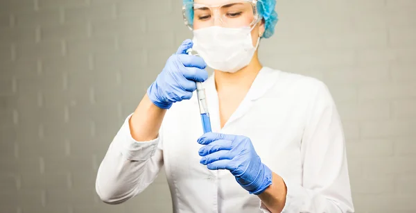 Female medical or scientific researcher with a test tube of clear solution in laboratory