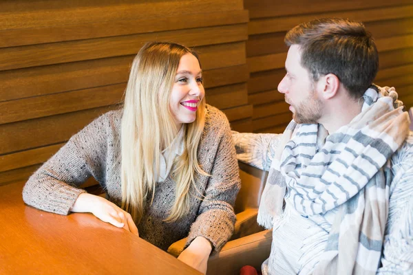 Woman talks with man sitting at the table in coffee house