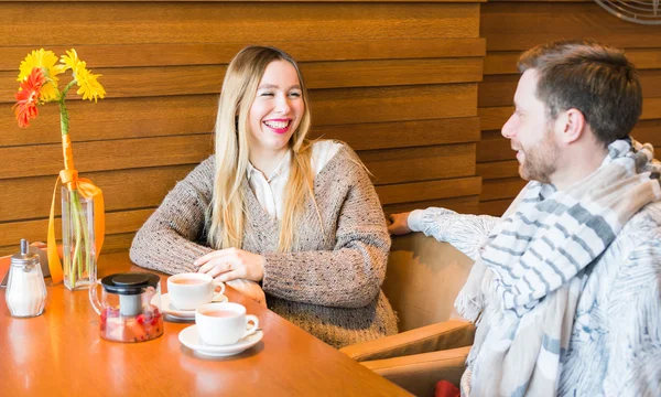 Woman talks with man sitting at the table in coffee house