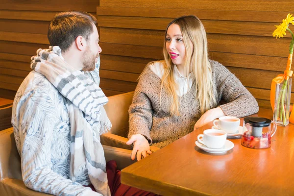 Woman talks with man sitting at the table in coffee house