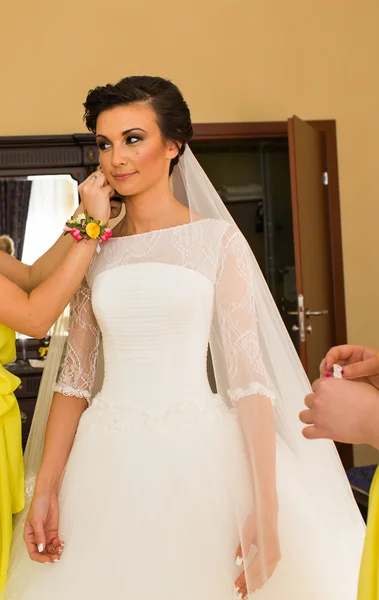 Beautiful young bride with makeup and hairstyle in bedroom, newlywed woman final preparation for wedding.