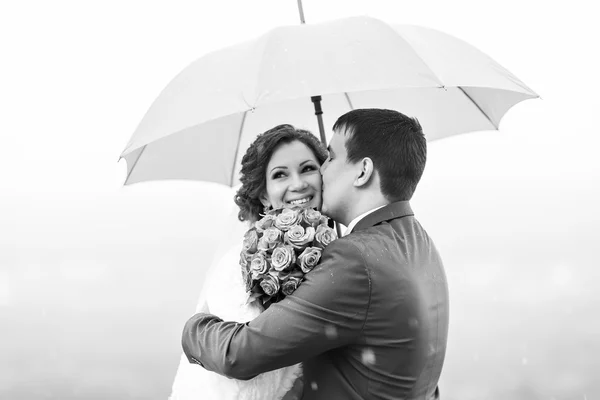 Just married couple have fun under umbrella