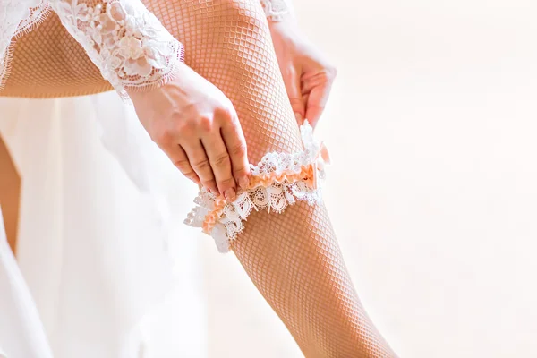 Bride dresses garter on the leg.