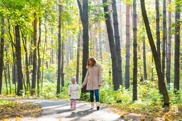 Mother and daughter walking in the autumn park