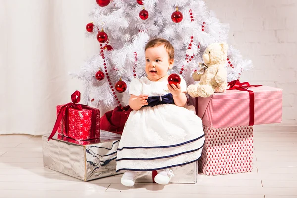 New year concept. Child baby toddler kid sitting under decorated christmas tree preparing presents gifts for celebration