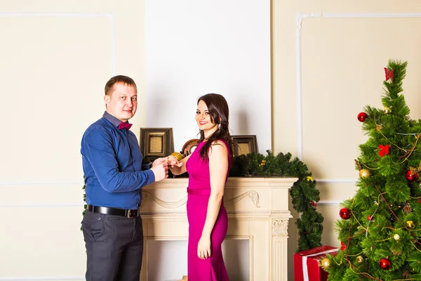 Will you marry me. Handsome young man making a proposal while giving an engagement ring to his girlfriend with Christmas Decoration in the background