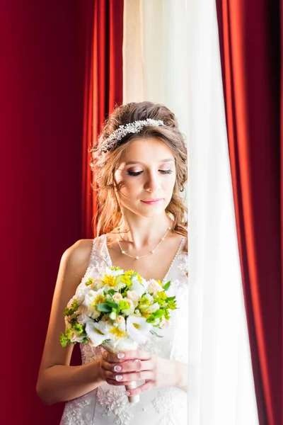 Beautiful young bride with wedding makeup and hairstyle in bedroom