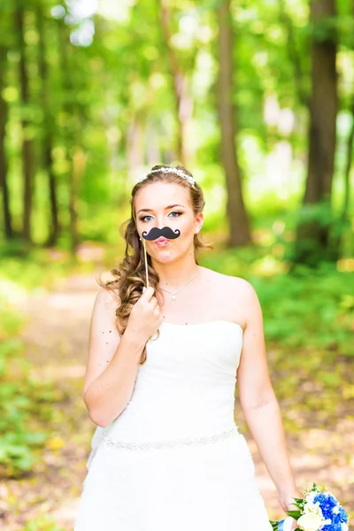 April Fools Day. Bride posing with stick lips, mask.