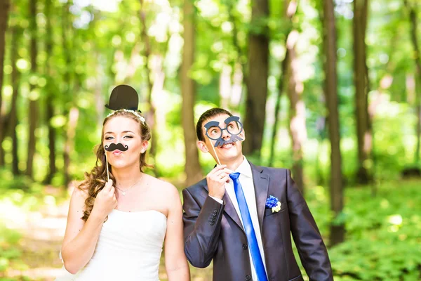 April Fools Day. Wedding couple posing with stick lips, mask.