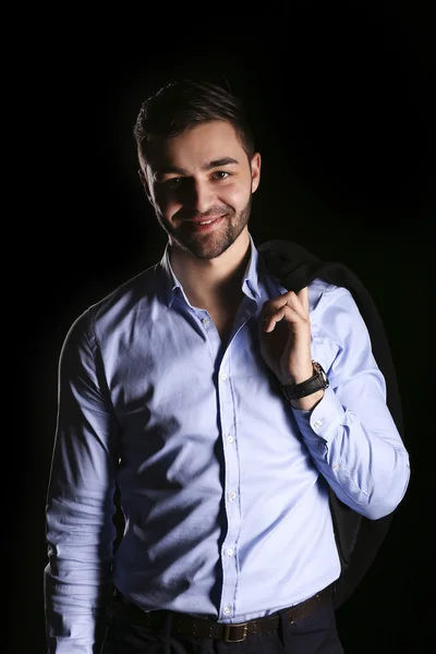 Casual young man  model holding a black jacket on a black background