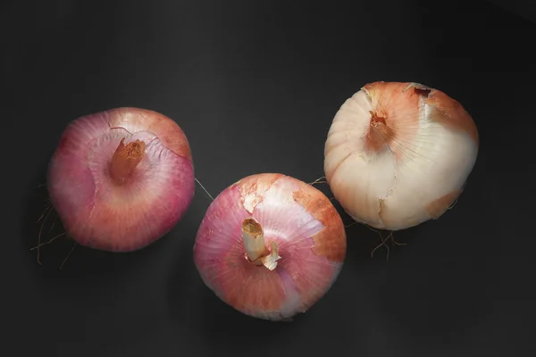 Three red onions isolated on a black background