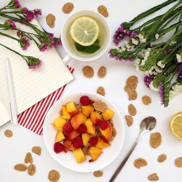 Flakes with fruits, cup of tea and flowers