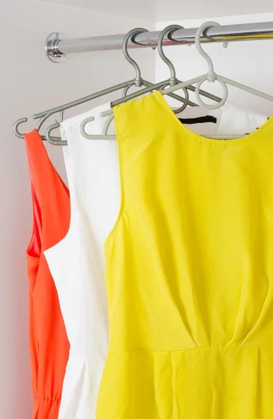 Row of bright colorful dress hanging on coat hanger in white war