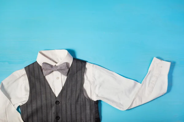 White shirt, gray vest and a bow tie on a bright blue background