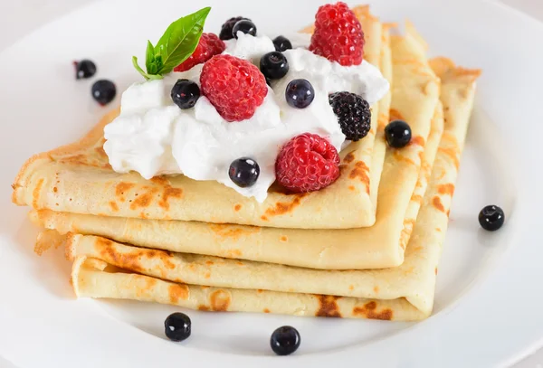 Delicious sweet crepes decorated air cream and ripe berries