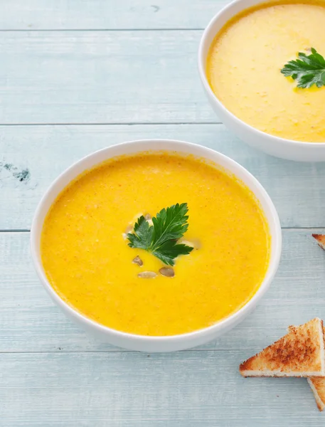 Pumpkin soup with parsley leaf on light background