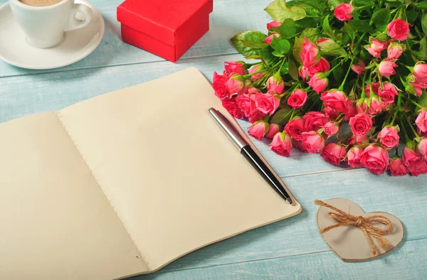 Open notebook with blank pages with bouquet of roses