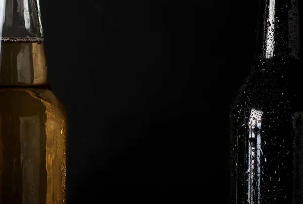 Two sweating, cold bottle of beer closeup on black background