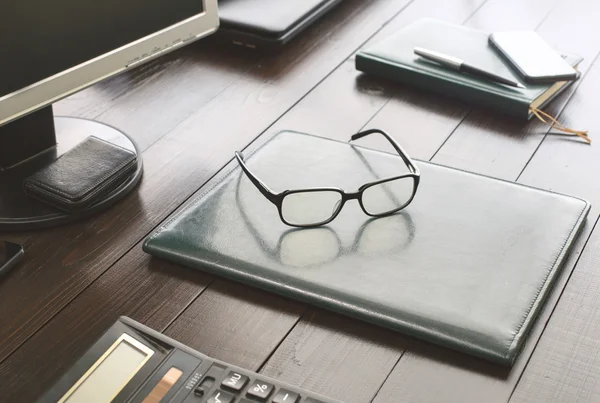 Glasses on the leather business folder on the office desktop