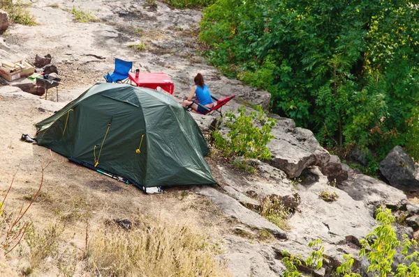 Green camping tent on a rock in the morning