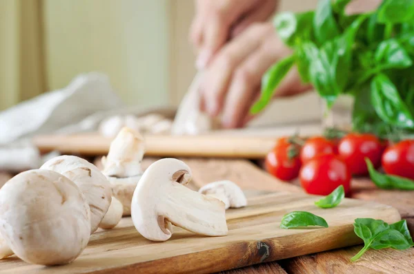 Sliced white button mushrooms on a cutting board with basil