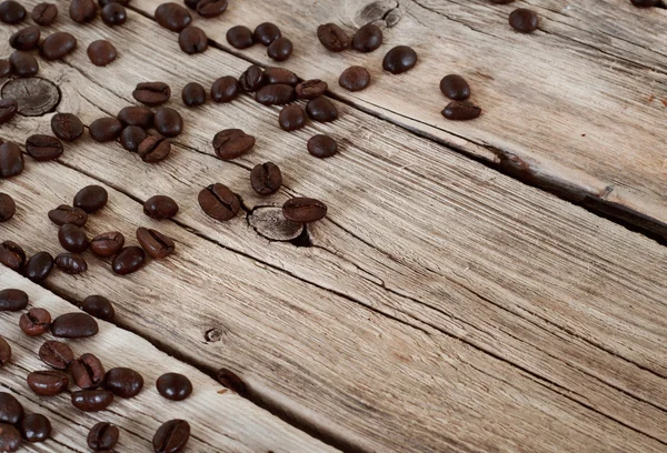 Spilled coffee beans on wooden table closeup