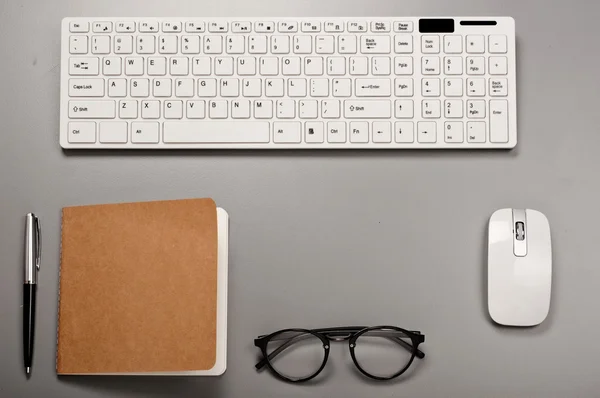 Office workstation with a keyboard, notebook, pen and glasses