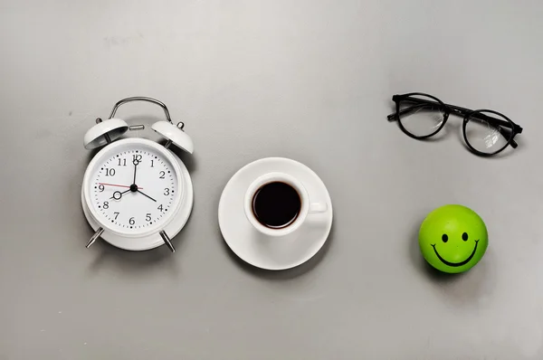 Cup of espresso with an alarm clock and glasses