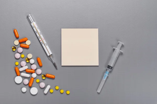 Paper for notes with a pills, capsules, thermometer and syringe