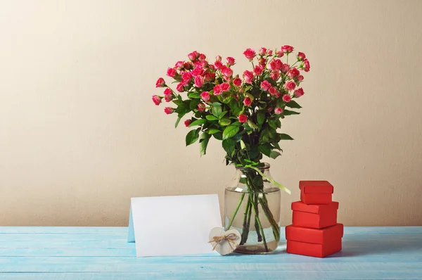 Bouquet of roses with blank greeting card and presents