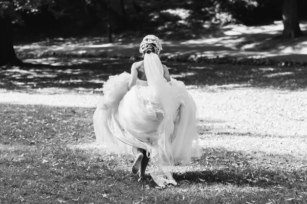 Happy beautiful bride dancing in park