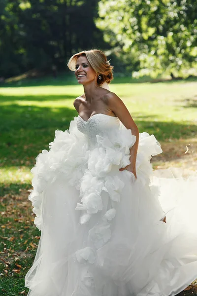 Happy beautiful bride dancing in park