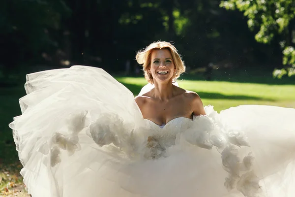 Happy beautiful bride dancing in park