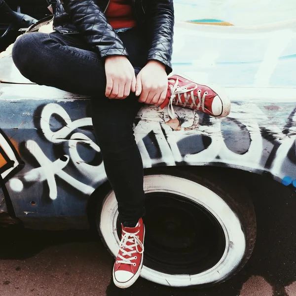 Legs of girl sitting on old car