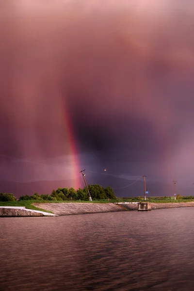 Red sky. on the lake. rainbow. red sunset after the rain. Low key, dark background, spot lighting, and rich Old Masters