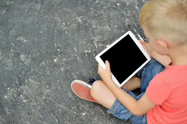 Teenage boy using a digital tablet in the street