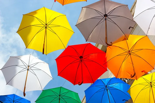 Colorful umbrellas against the sky in city settings.