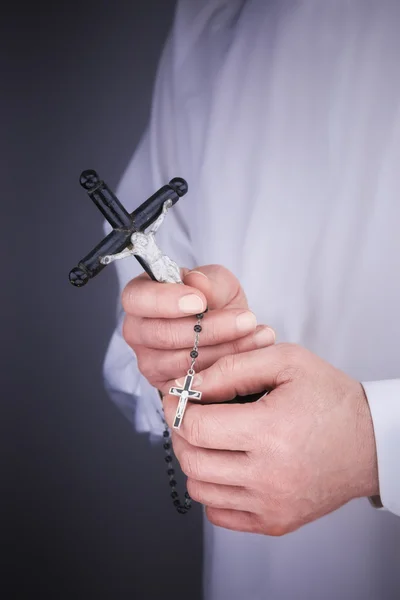Man\'s hands with a white cape, crucifix and a black rosary