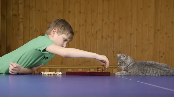 Teenage boy playing chess with a cat on a tennis table