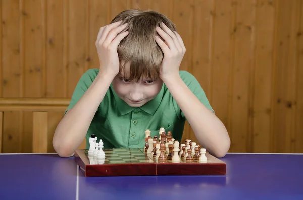Teen boy is thinking about a game of chess