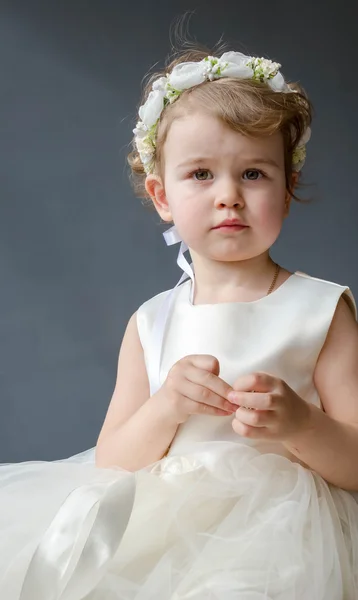 Beautiful little girl in white dress playing with jewelry