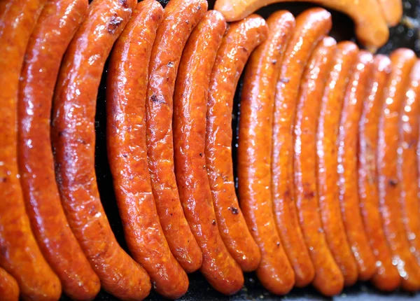 Group of sausages baking on hot iron plates
