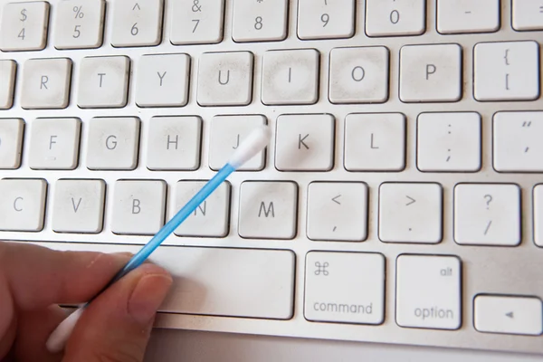 Hand cleaning dirty metallic computer keyboard