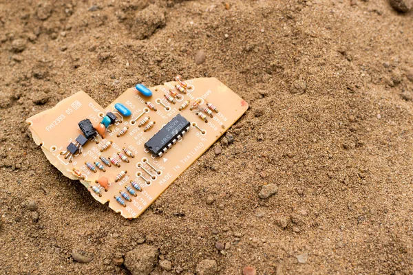 Broken circuit board on sand