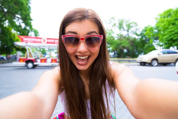 Close-up of trendy funny girl face in sunglasses is making selfie photo.Pretty young female tourist takes travel selfie in Odessa.Outdoor portrait of pretty student girl taking a selfie.
