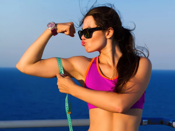 Fitness woman showing fresh energy flexing biceps muscles.